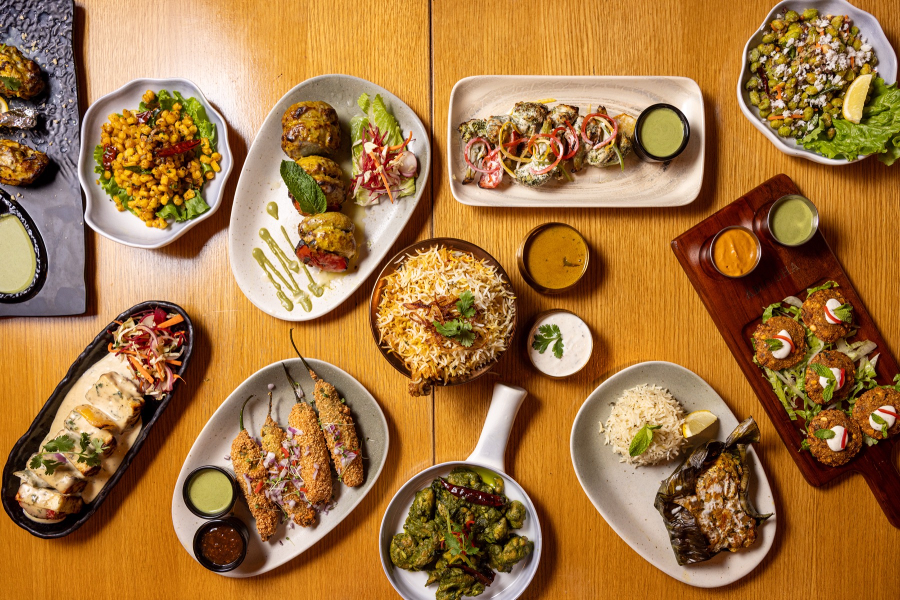 A top-down spread of Amogha dishes on a wooden table